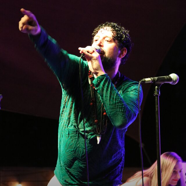 Frederico7 & Banda — Frederico7 singing into the microphone with his arm raised on stage