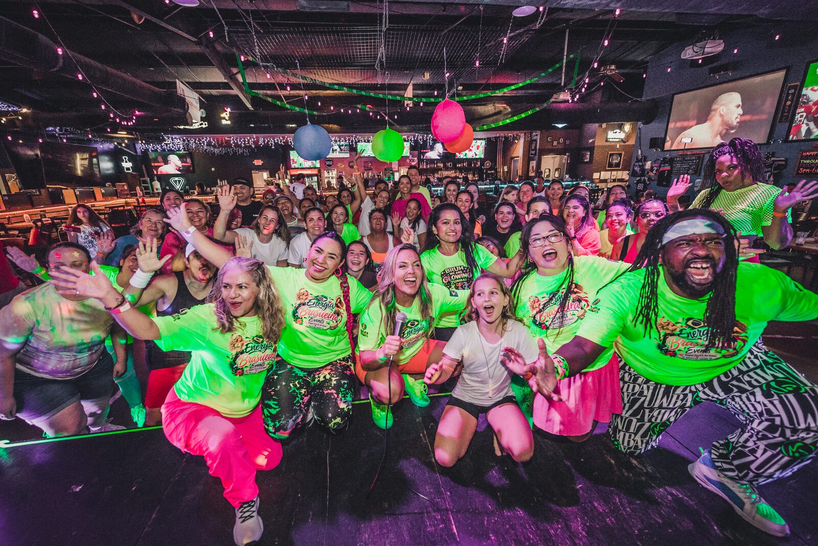 Guests in neon shirts posing together at a glow party.