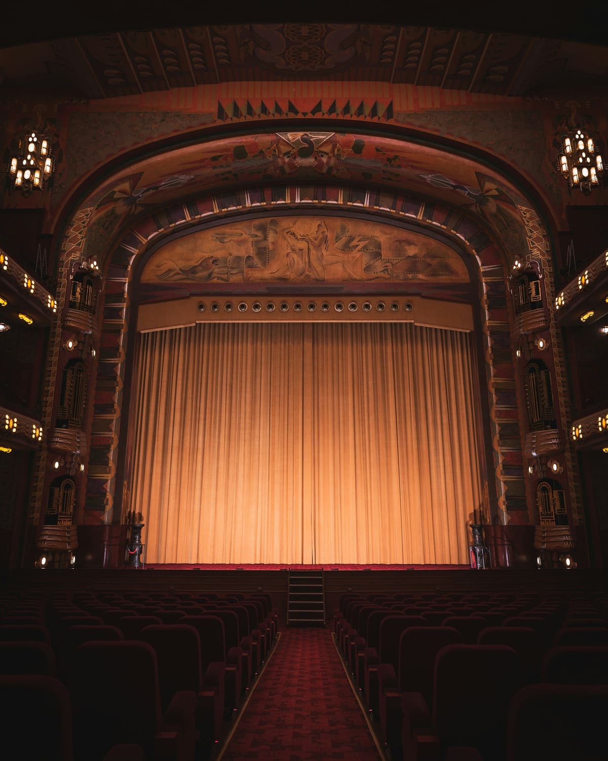 A gilded theater with the curtain lit before the show