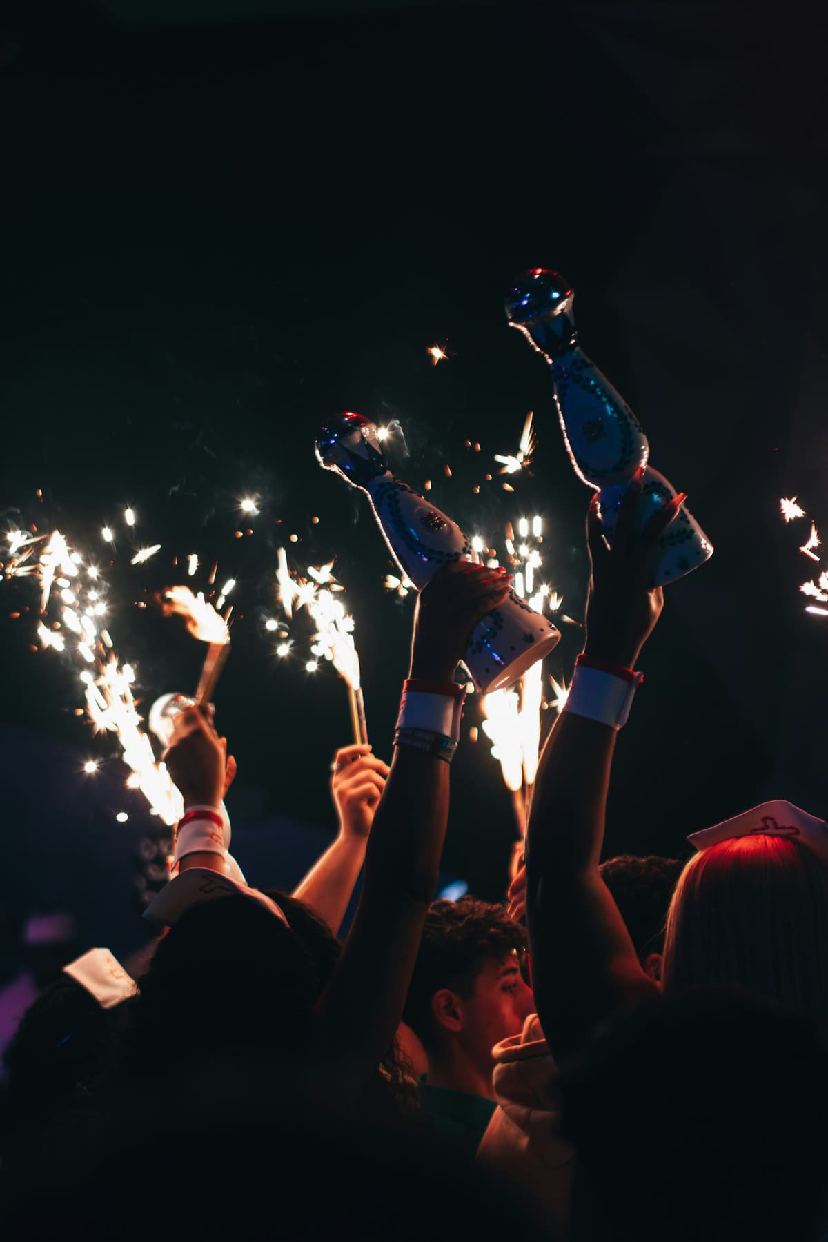 Bottles with sparklers held over a dark club crowd