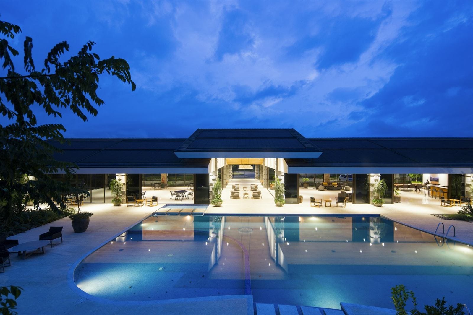 A hotel pool and lobby lit up at dusk